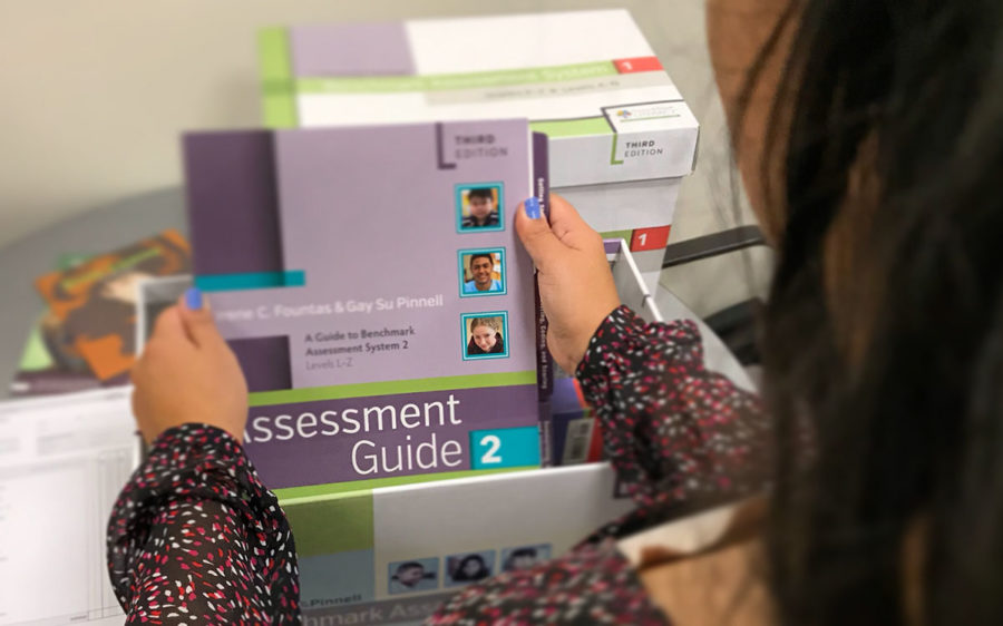 A person holding an Assessment Guide from the Benchmark Assessment System kit.